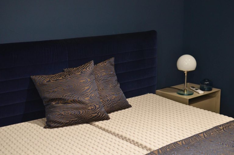 Creative design of bedroom interior with bed and pillows with ornament near lamp on bedside table
