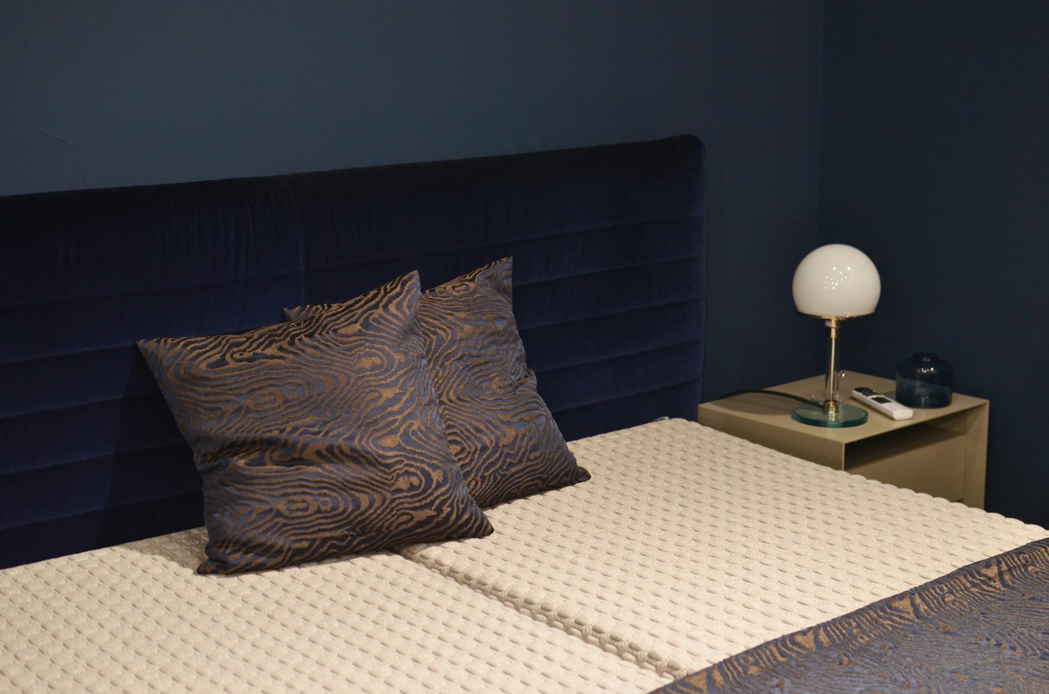 Creative design of bedroom interior with bed and pillows with ornament near lamp on bedside table